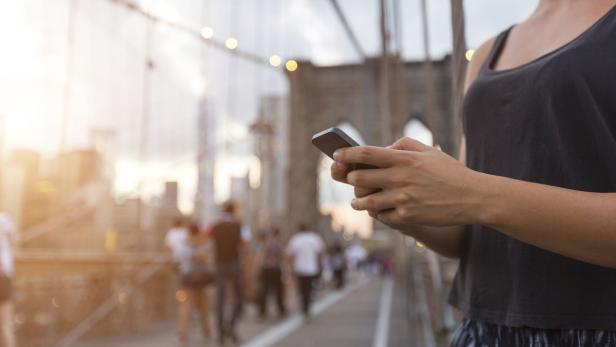 Eine Frau benutzt ihr Smartphone auf der Brooklyn Bridge.