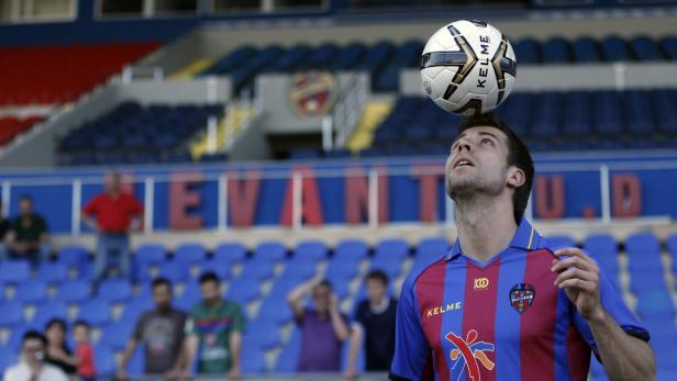 Ein Fußballspieler balanciert einen Ball auf dem Kopf im Stadion.