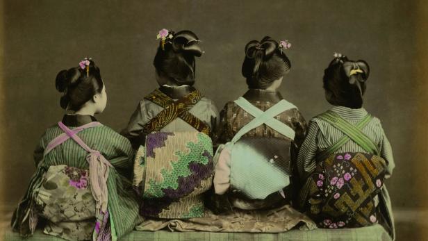 Vier japanische Frauen in Kimonos sitzen mit dem Rücken zum Betrachter.