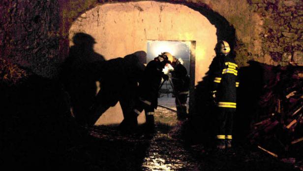 Feuerwehrleute arbeiten im Scheinwerferlicht in einem dunklen Tunnel.