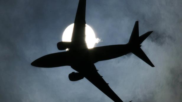 Die Silhouette eines Flugzeugs vor der Sonne.