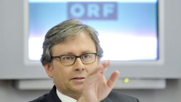 Ein Mann mit Brille gestikuliert vor einem Bildschirm mit dem ORF-Logo.