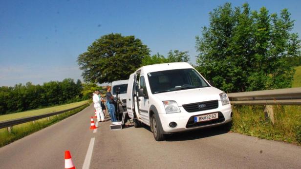 Ein Filmteam dreht eine Szene mit einem weißen Lieferwagen am Straßenrand.