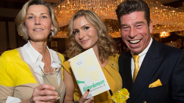 Drei Personen posieren mit dem Buch „Bitterlemon“ von Christiane Twister vor einem Kronleuchter.