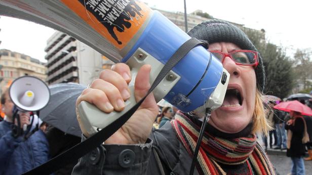 EPAepa03095442 Protesters shout into megaphones as they march under heavy rain in front of the Greek Parliament during a general strike protest in Athens, Greece, 07 February 2012. Greek political leaders will meet in the evening to decide whether to appr