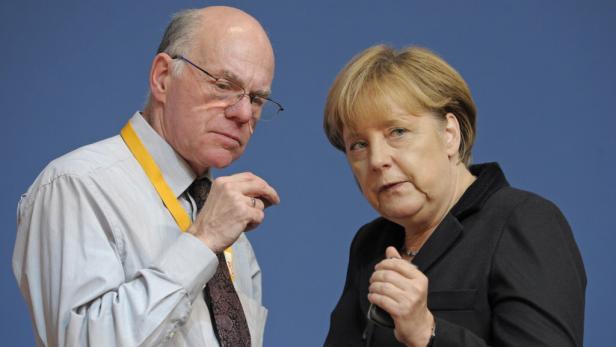 Angela Merkel im Gespräch mit einem Mann vor einem blauen Hintergrund.