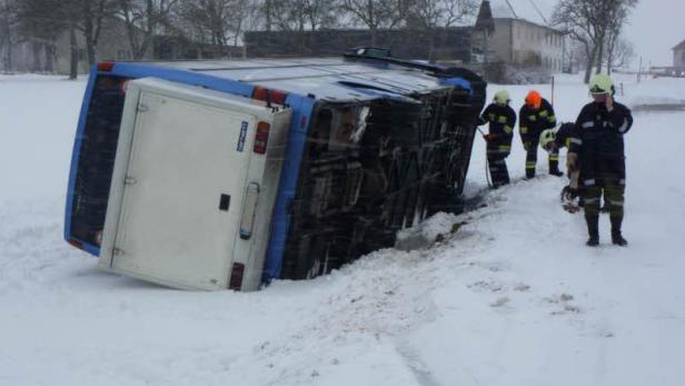 Ein umgekippter Lieferwagen im Schnee, umgeben von Feuerwehrleuten.