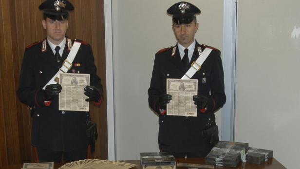Zwei Carabinieri präsentieren beschlagnahmte gefälschte Geldscheine.