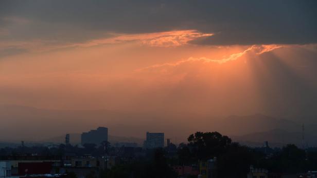 Sonnenstrahlen scheinen durch die Wolken über eine Stadtlandschaft.