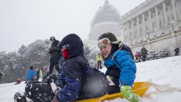 Zwei Kinder rodeln im Schnee vor dem Kapitol in Washington, D.C..