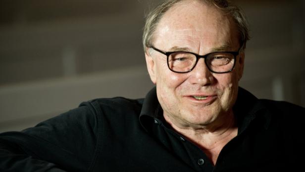 Ein Mann mit Brille und schwarzem Hemd lächelt.