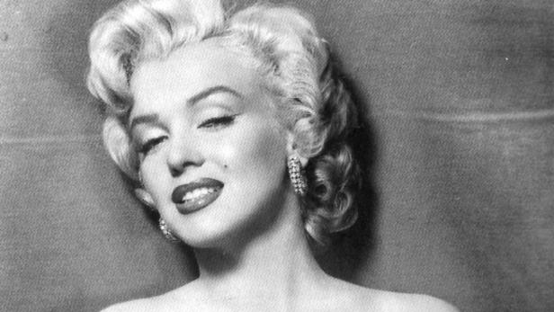 Ein Schwarzweißporträt von Marilyn Monroe mit hochgestecktem, blondem Haar und Ohrringen.