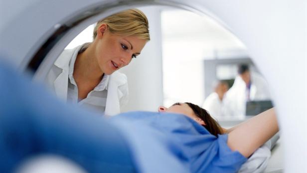 Eine Patientin liegt in einem CT-Scanner, während eine Ärztin sie beobachtet.