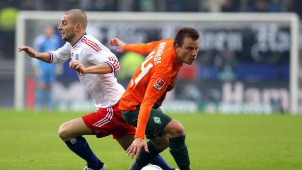 Zwei Fußballspieler kämpfen um den Ball auf dem Spielfeld.