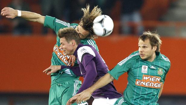 Zwei Fußballspieler kämpfen um den Ball, wobei einer den Ball mit dem Kopf berührt.