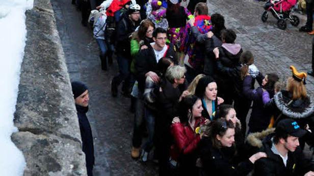 Eine Menschenmenge steht an einem Wintertag an einer Straße.