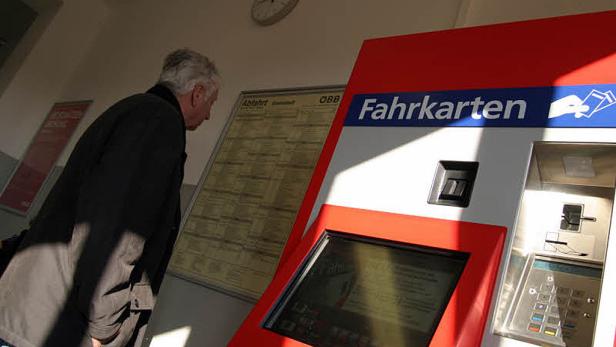 Ein Mann studiert einen Fahrplan neben einem Fahrkartenautomaten.