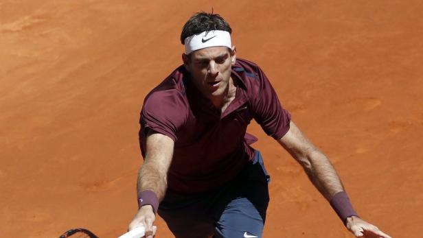 Ein Tennisspieler mit Stirnband schlägt einen Ball auf einem Sandplatz.