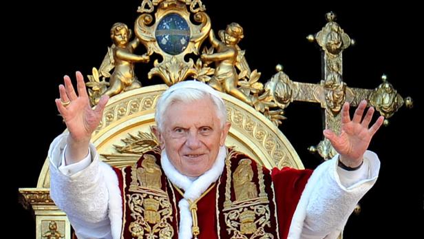 Papst Benedikt XVI. winkt von einem reich verzierten Balkon.