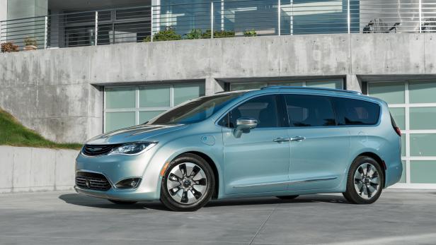 Ein hellblauer Chrysler Pacifica Hybrid vor einem modernen Haus.