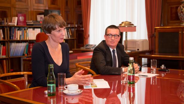 Eine Frau und ein Mann sitzen an einem Tisch in einem Büro und unterhalten sich.