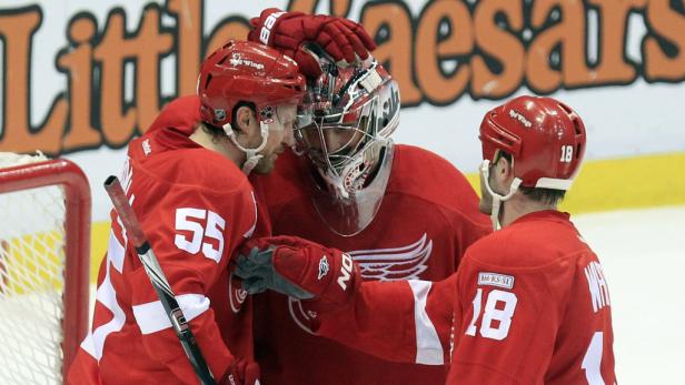 Ein Eishockeytorwart der Detroit Red Wings umarmt zwei seiner Teamkollegen.