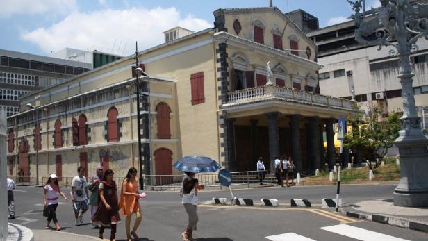 Eine Gruppe von Menschen überquert eine Straße vor einem historischen Gebäude.