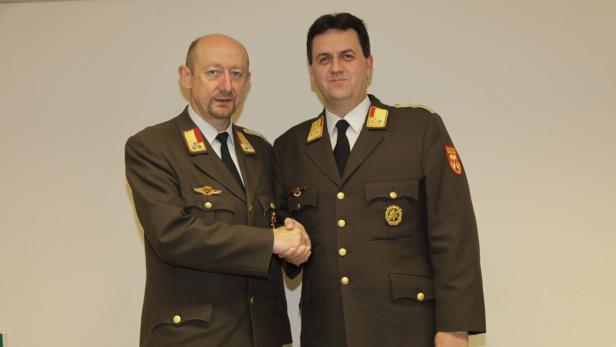Zwei Männer in Uniformen schütteln sich die Hände.