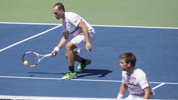Ein Tennisspieler schlägt den Ball auf einem blauen Platz.