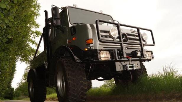 Ein grauer Mercedes-Benz Unimog steht auf einer asphaltierten Straße.