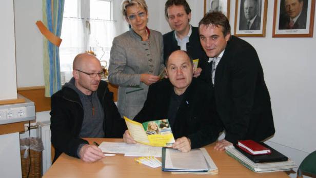 Eine Gruppe von fünf Personen posiert an einem Tisch für ein Foto.