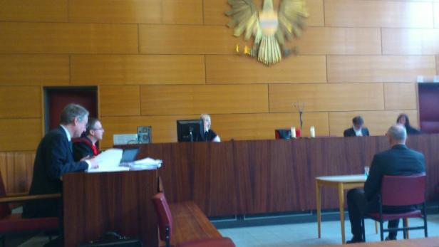 Eine Gerichtsszene mit Richtern und Anwälten in einem Gerichtssaal.