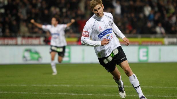 Ein Fußballspieler in weiß-schwarzer Uniform läuft auf dem Spielfeld.