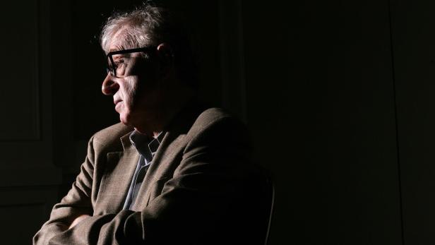 Woody Allen im Profil, mit verschränkten Armen und Brille.