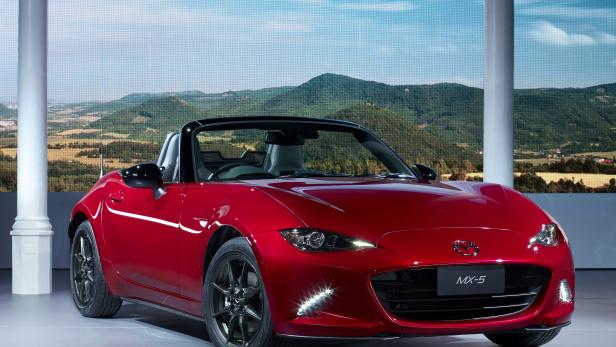 Ein roter Mazda MX-5 Roadster vor einer Landschaftskulisse.