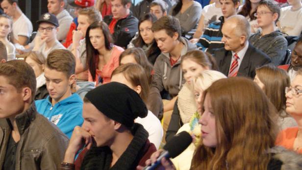 Eine große Gruppe von Menschen sitzt in einem Publikum.