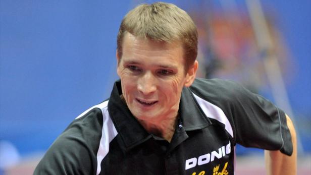 Ein Tischtennisspieler in Sportkleidung mit dem Logo eines Sponsors.