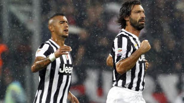 Arturo Vidal und Andrea Pirlo im schwarz-weiß gestreiften Trikot während eines Fußballspiels im Regen.