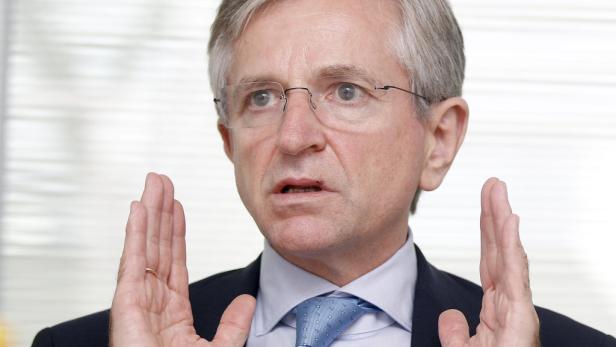 Ein Mann mit Brille und Anzug gestikuliert mit beiden Händen.