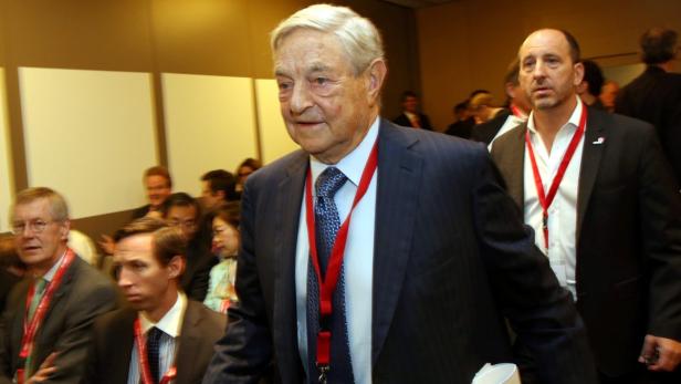 George Soros auf einer Konferenz, umgeben von anderen Teilnehmern.