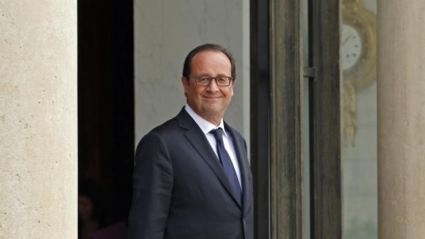 François Hollande steht vor einer Tür mit Säulen.
