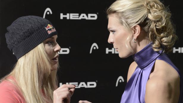 Zwei blonde Frauen unterhalten sich vor einem schwarzen Hintergrund mit dem Head-Logo.