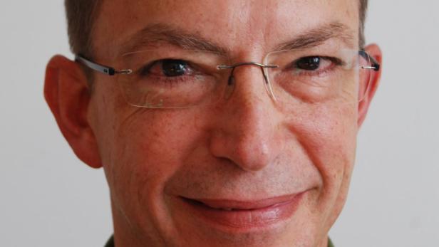 Porträt eines Mannes mit Brille, der lächelt.