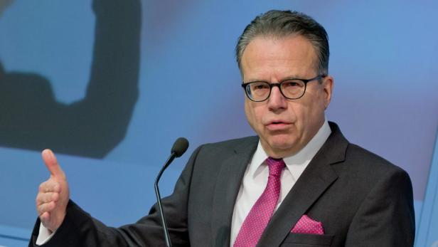 Ein Mann in Anzug und Brille spricht vor einem Hintergrund der Bundesagentur für Arbeit.