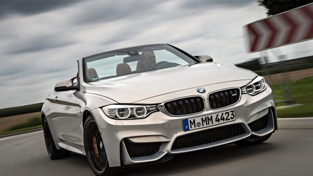 Ein silbernes BMW M4 Cabriolet fährt auf einer kurvenreichen Straße.