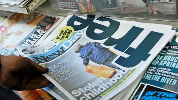 Eine Hand greift nach einer Ausgabe der Zeitung „New Day“.