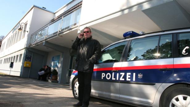 Ein Mann in Lederjacke telefoniert vor einem Polizeiauto.