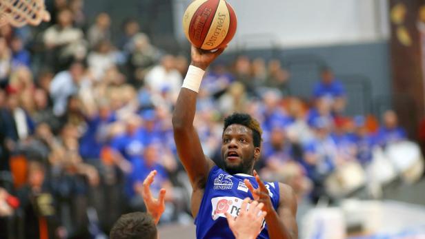Ein Basketballspieler in blauem Trikot wirft einen Spalding-Ball.