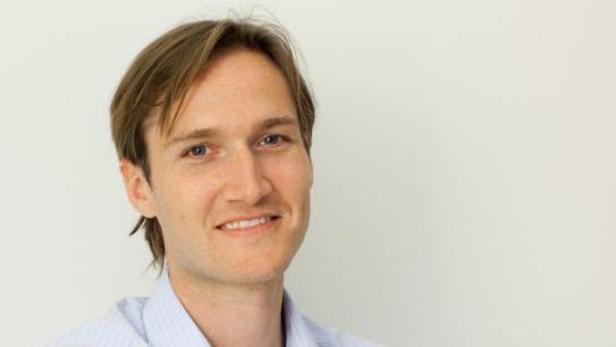 Ein Mann mit blonden Haaren lächelt in die Kamera.