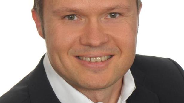 Ein Mann im Anzug lächelt in die Kamera.